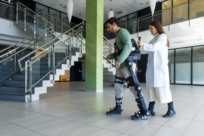 Stampa con cornice : Esoscheletro meccanico, dottore fisioterapista donna che cammina con persona disabile aiutata da scheletro robotico. Stampa con cornice : Esoscheletro meccanico, dottore fisioterapista donna che cammina con persona disabile aiutata da scheletro robotico.