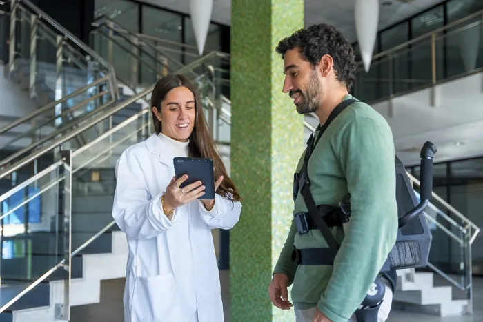 Stampa con cornice : Esoscheletro meccanico, fisioterapista donna che parla con un tablet con una persona disabile con scheletro robotico. Stampa con cornice : Esoscheletro meccanico, fisioterapista donna che parla con un tablet con una persona disabile con scheletro robotico.