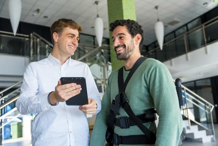 Stampa con cornice : Esoscheletro meccanico, fisioterapista che guarda la consultazione con tablet con persona disabile con scheletro robotico.