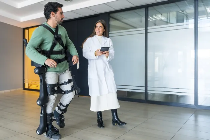 Stampa con cornice : Esoscheletro meccanico, dottoressa fisioterapista femmina che cammina con persona disabile aiutata da scheletro robotico. Stampa con cornice : Esoscheletro meccanico, dottoressa fisioterapista femmina che cammina con persona disabile aiutata da scheletro robotico.
