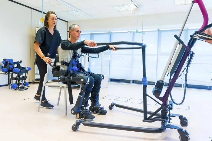 Stampa con cornice : Esoscheletro meccanico. Assistente fisioterapista donna che solleva una persona disabile con scheletro robotico per farla alzare. Stampa con cornice : Esoscheletro meccanico. Assistente fisioterapista donna che solleva una persona disabile con scheletro robotico per farla alzare.
