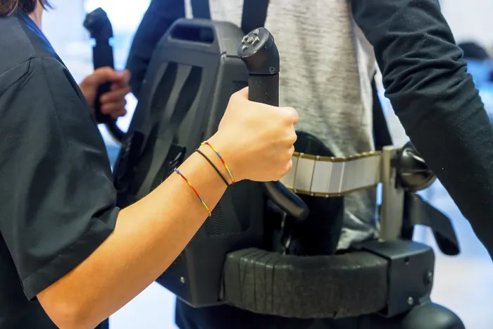 Stampa con cornice : Esoscheletro meccanico. Assistente fisioterapista femminile aiuta persona disabile con scheletro robotico a camminare. Stampa con cornice : Esoscheletro meccanico. Assistente fisioterapista femminile aiuta persona disabile con scheletro robotico a camminare.