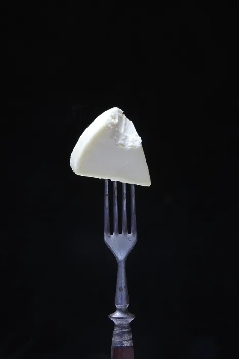 Stampa con cornice : Formaggio processato su forchetta, morso. Stampa con cornice : Formaggio processato su forchetta, morso.