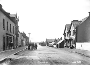 Stampe di Groomsport - una vista della Main street con un'auto a motore e bambini intorno. Ci sono una varietà di edifici interessanti su entrambi i lati della strada e un negozio al centro In Basso Stampe: Groomsport