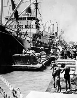 Stampe di Scaricando una merci di carico da navi nei moli del porto di Manilla, Filippine. Tre giovani uomini indossano pantaloni corti e si asciugano il sudore dalla loro pelle in questo caldo estivo Filippine Stampe: Darsena di Manila