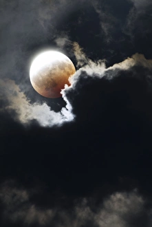 Stampe di Eclissi lunare parziale vista attraverso le nuvole. La porzione più luminosa della Luna continua a riflettere il sole lampante Immagini datate 2009 maggio: Eclisse lunare parziale