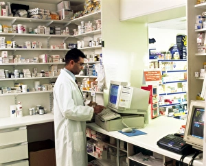 Stampe di Modello rilasciato. Farmacista. Veduta di un farmacista che utilizza il computer per compilare una scheda del paziente, la quale elenca le varie medicine prescritte dal negozio di farmacia al paziente Immagini datate 2003 settembre: Farmacista che utilizza un computer in una farmacia