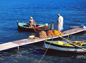 Stampe di Il pescatore e sua moglie puliscono le reti da pesca nella barca e nel molo a Corfù, Isole Greche, Grecia Europa Immagini del 18 giugno 2010: Corfou