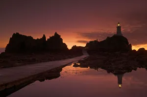 European Island Getaways Stampe: Dramatic sunset, low tide, Corbiere lighthouse, St. Ouens, Jersey, Channel Islands