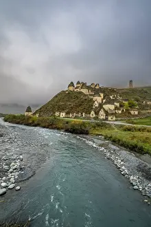 Stampe di Esplorando strutture antiche nella città dei Morti, Dargavs, situata in Ossezia del Nord, Russia, vicino a un fiume che scorre e colline ondulate Architettura Russa Stampe: Esplorando strutture antiche nella città dei Morti