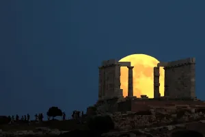 Stampe di Le persone guardano una luna piena che sorge dietro il Tempio del Posidone prima dell'eclissi lunare a Cape Sounion, vicino ad Atene, in Grecia, 27 luglio 2018 Eclissi Stampe: Ombra lunare nella Grecia