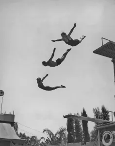Stampe di Due donne e un uomo in aria dopo aver usato una piattaforma salti al Ambassador Lido pool a Los Angeles, California circa gli anni '40. (Foto di Keystone View/FPG/Getty Images) Immagini in bianco e nero che catturano l'essenza della metà del XX secolo: Usando La Piattaforma di Salto.