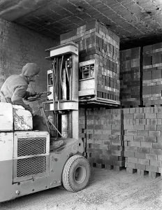 Michael Walters Photography UK Stampe: A yardsman stacking pallets of bricks