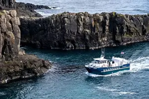 Il traghetto supera scogliere drammatiche nel suo percorso verso il molo.
