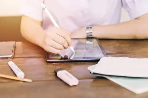 Studente di scuola che utilizza un dispositivo computer portatile touchscreen per imparare e scrivere compiti, tecnologia moderna per l'istruzione.