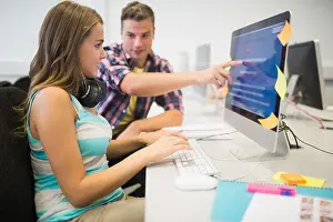 Compagni di classe che sorridono facendo un compito insieme nella sala computer.