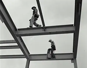 Low Angle View Photography Stampe: Two construction workers walking on the frame of a grain elevator