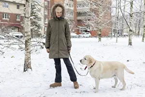 Winter Portrait Stampe: Affection Moment. Outdoor winter scene where woman shares tender moment with pet dog surrounded by snow and bare trees