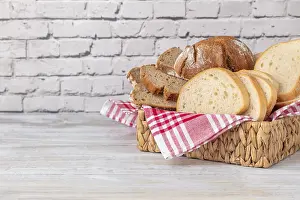 Diverse Bread Types Stampe: A basket with different types of bread on a brick wall