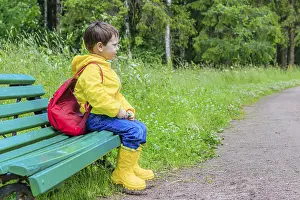 Young Boy Portrait Stampe: A boy with a backpack is sitting on a bench