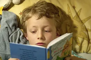 Boy Reading In Bed Stampe: Boy reading in bed