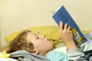 Boy Reading In Bed Stampe: Boy reading in bed