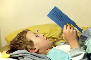 Boy Reading In Bed Stampe: Boy reading in bed