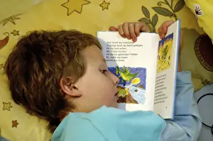 Boy Reading In Bed Stampe: Boy reading in bed