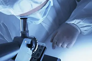 Chemist In Lab Coat Stampe: Chemist looking through a microscope
