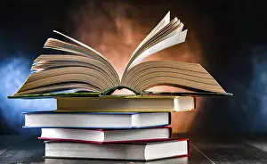 Book Stack Stampe: A composition with an open book lying on a stack of other books