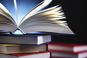 Piled Up Books Stampe: A composition with an open book lying on a stack of other books