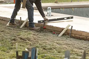 Building Inspection Stampe: Construction worker checking level on wet deck cement