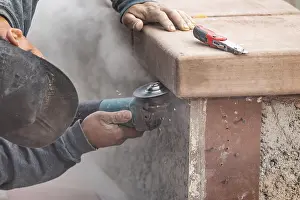 Construction Industry Workers Stampe: Construction worker using grinder at construction site