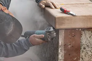 Construction Industry Workers Stampe: Construction worker using grinder at construction site