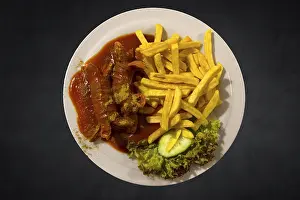 Meat Products Nutrition Stampe: Currywurst with chips on a dark background
