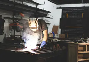 Factory Interior Photography Stampe: Deaf man using a welding torch in the workshop