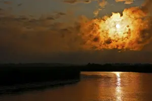 Atmospheric Evening Light Sky Stampe: Dramatic cloud formation at sunset reflected in a calm river
