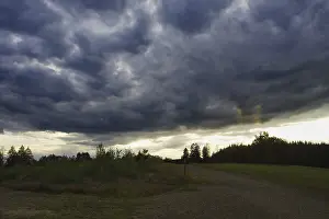 Weather Forecast Images Stampe: Dramatic, dark clouds drift across a landscape at dusk