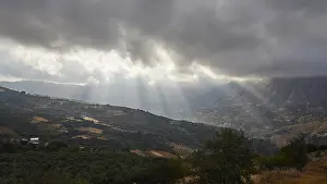 Greek Island Landscapes Stampe: Dramatic landscape with sun rays breaking through a cloud cover