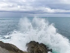 Panoramic Ocean View Stampe: A dramatic scene as powerful waves collide with rugged rocks under a brooding sky
