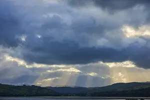 Dramatic Mountain Landscape Stampe: Dramatic sky with rays of light breaking through the clouds over a mountainous landscape