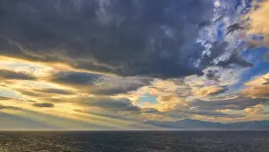 Cloudy Atmospheric Images Stampe: Dramatic sky over the sea with sun rays breaking through the clouds