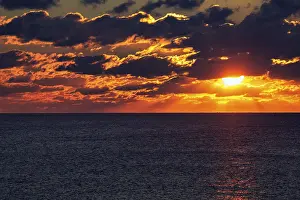 Dramatic Sunset Stampe: Dramatic sunset at the sea, sunbeams behind clouds