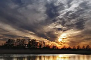 Natural Preserve In Eastern Germany Stampe: Dramatic sunset sky with trees and soft reflection in water