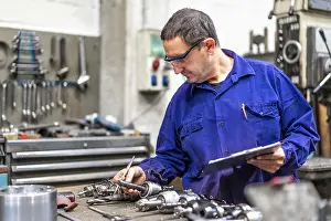 Factory Worker Stampe: Factory worker operator of the numerical control sector measuring the drill bits