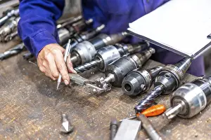 Factory Worker Stampe: Factory worker operator of the numerical control sector measuring the drill bits
