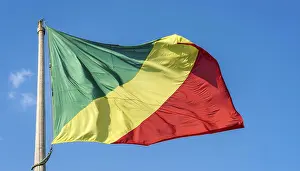 Stampe di La bandiera del Congo sventola al vento, isolata contro un cielo azzurro Brazzaville Stampe: La bandiera del Congo sventola nel vento.