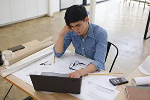 Building Architecture Plans Stampe: A focused architect and engineer using a laptop to work on blueprints