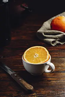 Rustic Table Setting Stampe: Half of orange in a white cup over rustic table