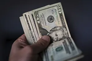 US Currency Stampe: A hand holds a stack of US currency